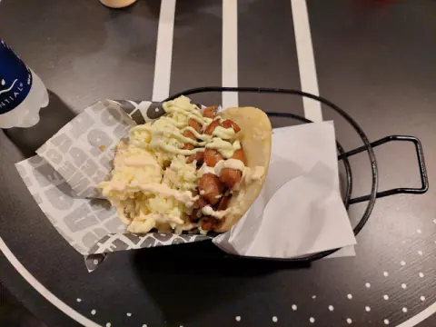 Arepa con salchicha, queso y salsas en su canasta