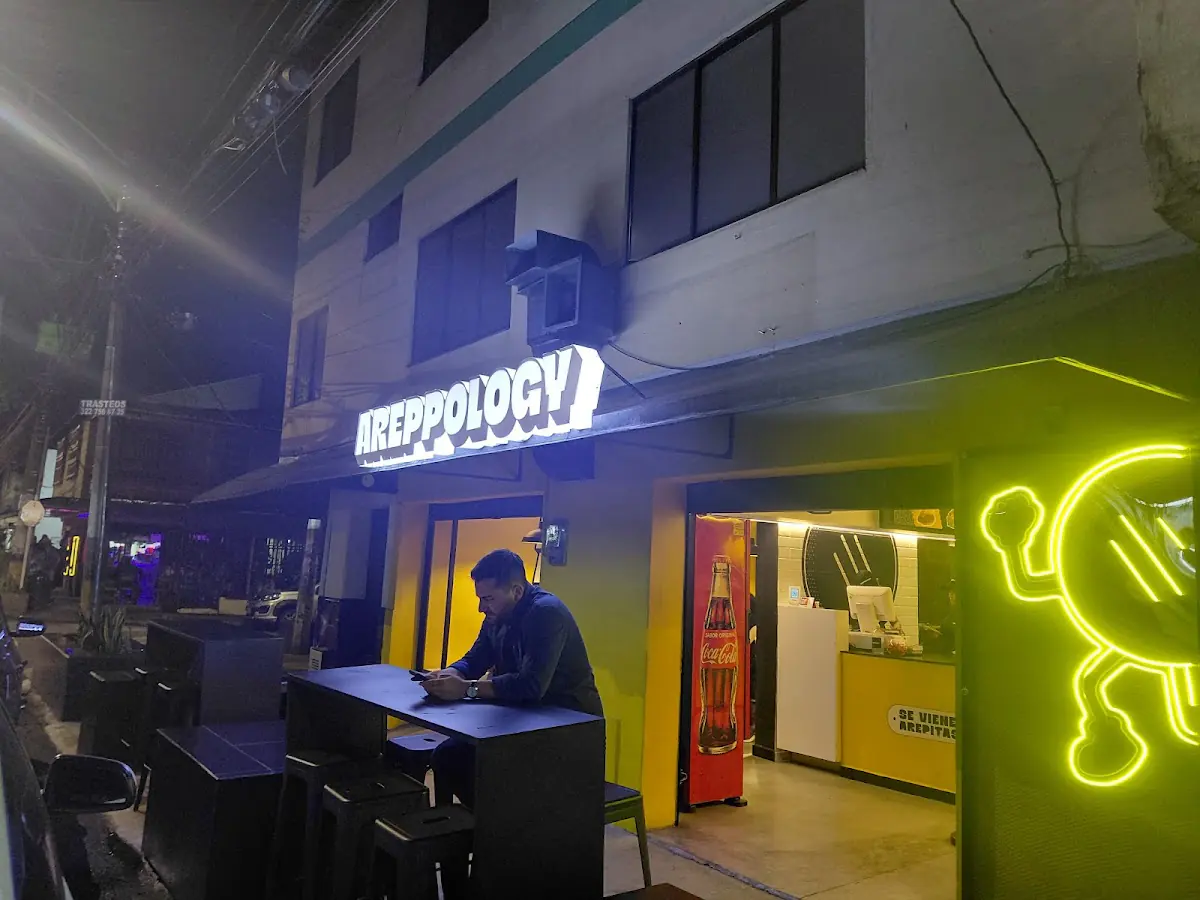 Local de Areppology de noche, con su aviso iluminado y un neón amarillo