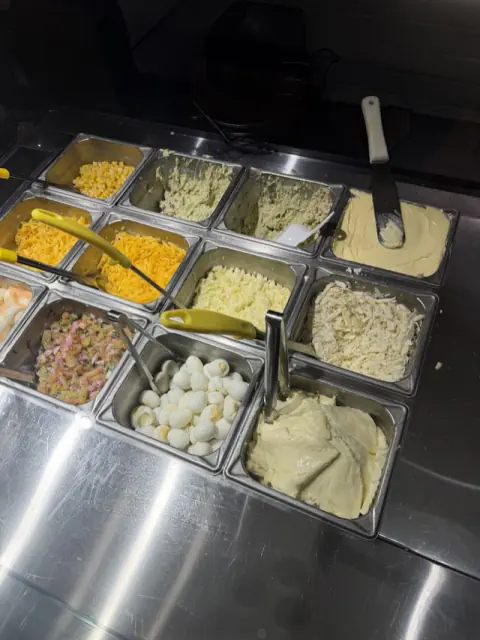 Barra de toppings con carnes, quesos y salsas